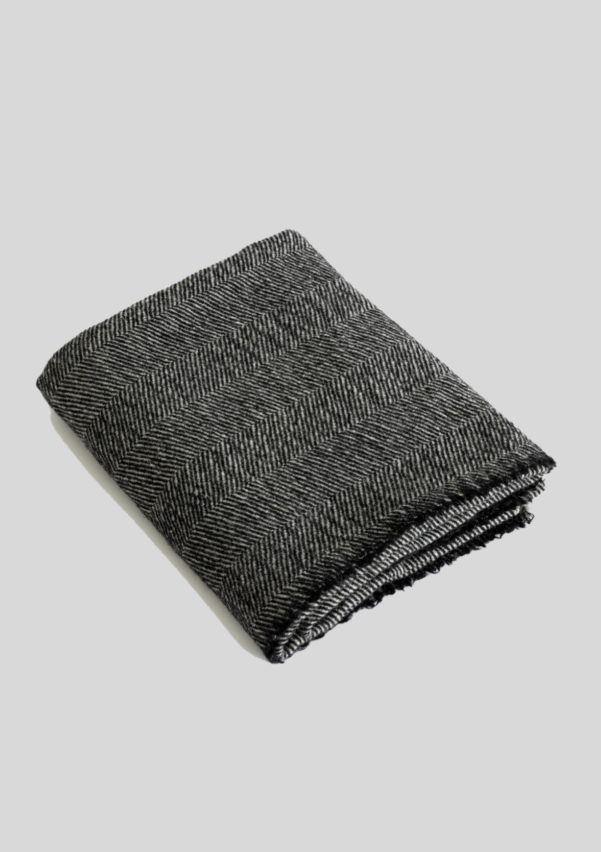 Herringbone pattern grey and black colored throw made out of responsible Finnish sheep wool. Manufactured in Finland.  