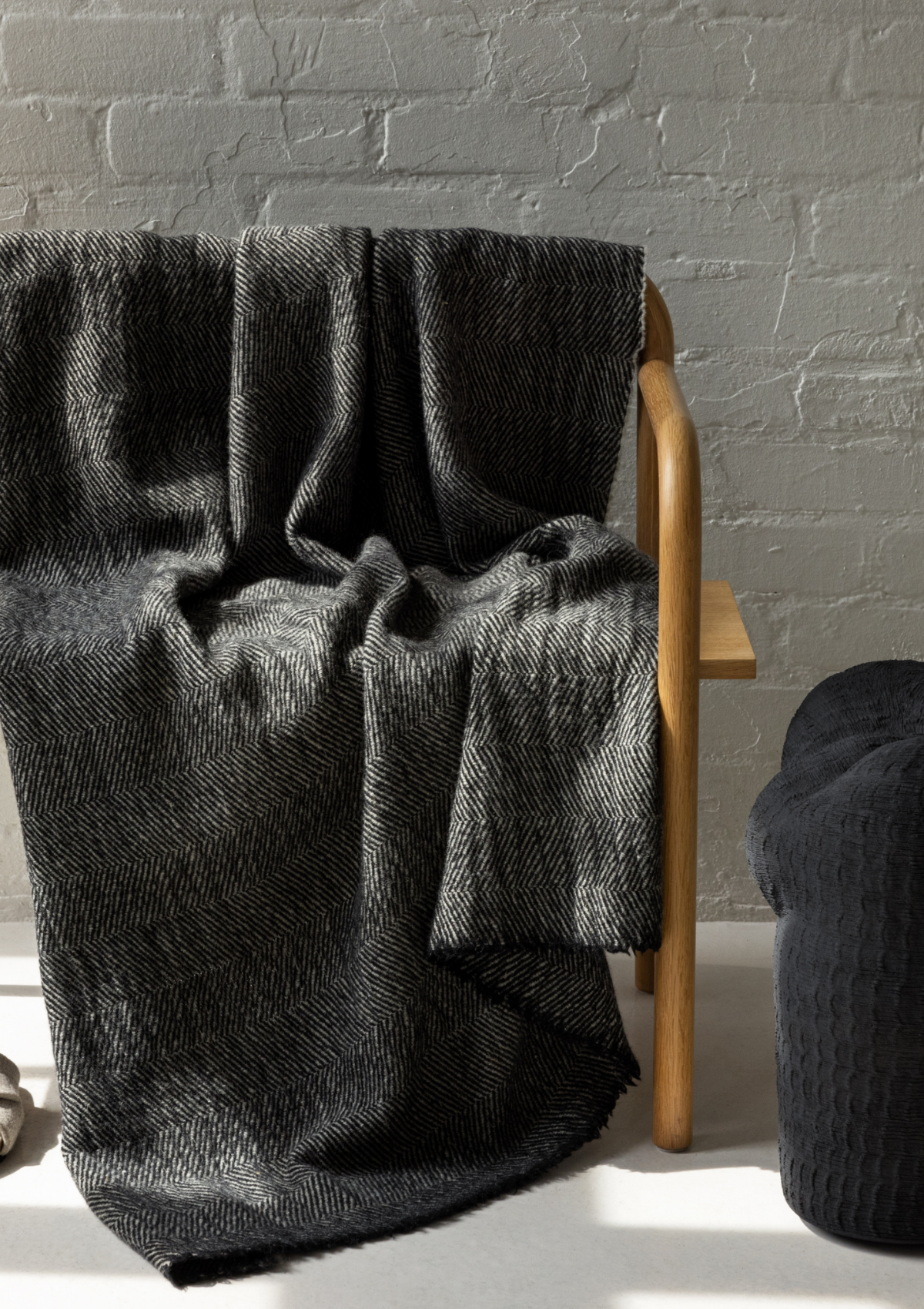 Herringbone pattern grey and black colored throw made out of responsible Finnish sheep wool. Manufactured in Finland.  